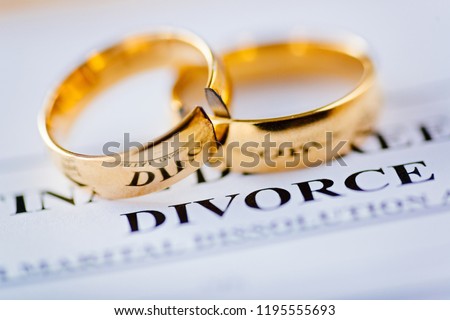 Two broken golden wedding rings divorce decree document. Divorce and separation concept Royalty-Free Stock Photo #1195555693