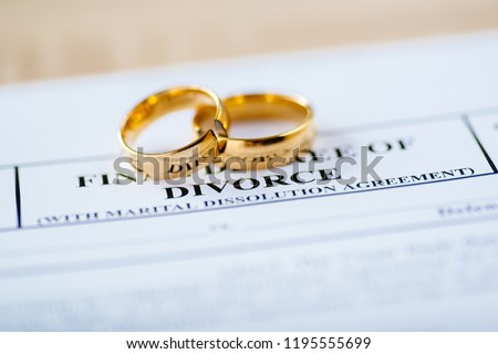 Two broken golden wedding rings divorce decree document. Divorce and separation concept Royalty-Free Stock Photo #1195555699