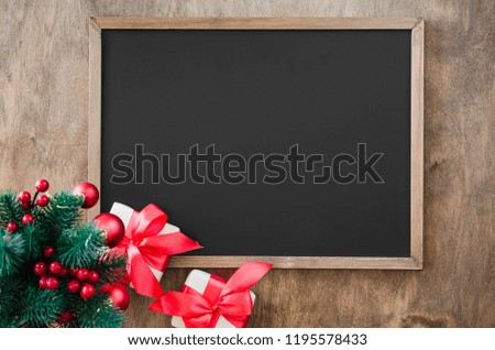 Empty blackboard with christmas decoration, red gift box, fir branches. Chalk board and Christmas trinkets. Xmas background with copy space for inscription, top view.