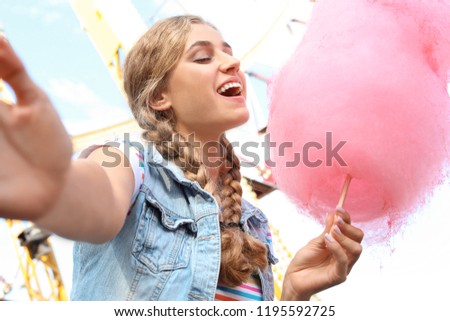 Attractive woman taking selfie with cotton candy in amusement park