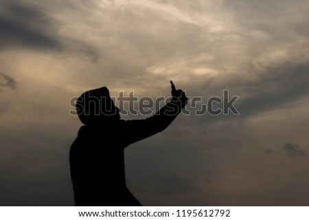 Man taking photos, selfie, by smartphone with twilight time in silhouette