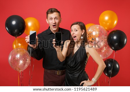 Couple hold in hand cellphone with blank screen celebrating birthday holiday party isolated on red background air balloons. St. Valentine International Women Day Happy New Year 2019 concept. Mock up