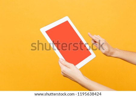 Close up female hold in hand tablet pc pad with blank empty screen with place for text or image, workspace isolated on trending yellow orange background. Technology concept. Copy space advertisement