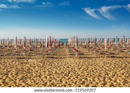withdrawn yellow umbrellas and sunlongers on the sandy beach in Italy Royalty-Free Stock Photo #119569207
