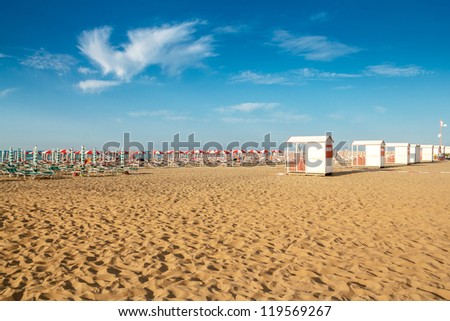red and white umbrellas and sunlongers on the sandy beach in Italy Royalty-Free Stock Photo #119569267