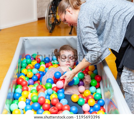 Disability a disabled child enjoying play therapy together with a special needs carer