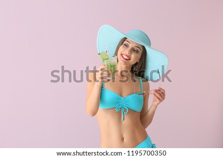 Beautiful woman in swimming suit and with tasty summer cocktail on color background