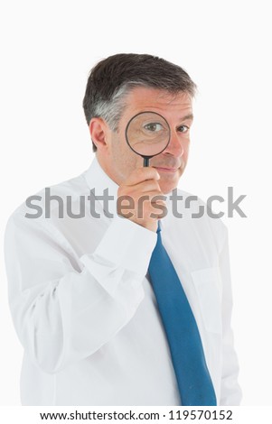 Inquisitive businessman looking through magnifying glass