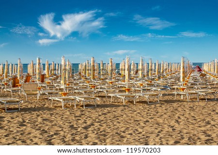withdrawn yellow umbrellas and sunlongers on the sandy beach in Italy Royalty-Free Stock Photo #119570203