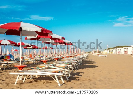 red and white umbrellas and sunlongers on the sandy beach in Italy Royalty-Free Stock Photo #119570206