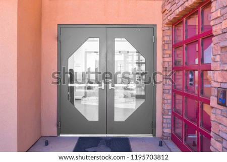 Outside solid glass red door with building exterior is orange.