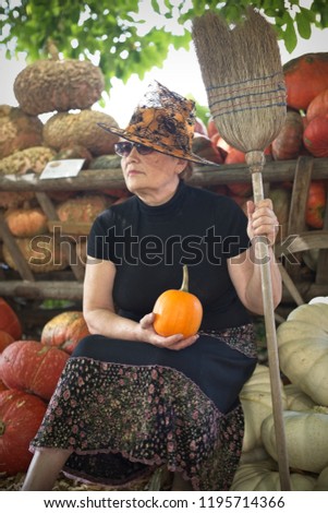 Friendly witch with broom on pumpkins background..Halloween personage