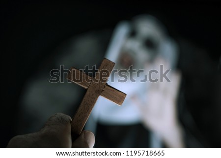 closeup a cross in the hand of a man and a frightening evil nun, wearing a typical black and white habit, screaming Royalty-Free Stock Photo #1195718665