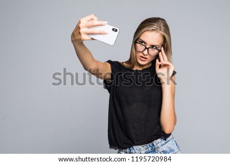 Happy cute woman making selfie over gray background.