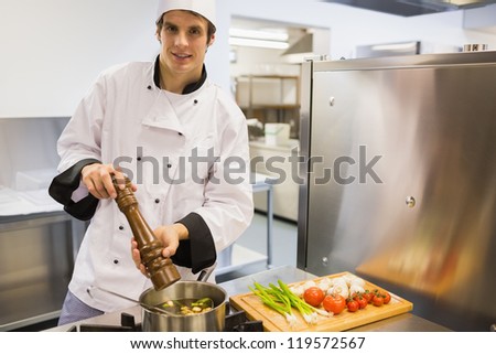 Chef putting pepper into soup in kitchen