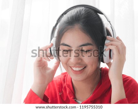Happy teenager girl in red hood using headphone at home.