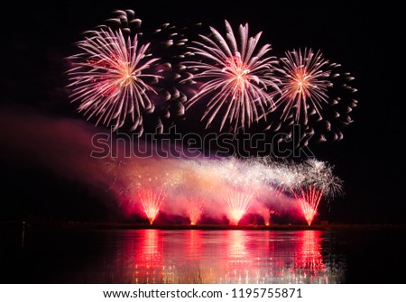Beautiful colorful holiday fireworks with reflections in the water on the black sky background, close-up, long exposure