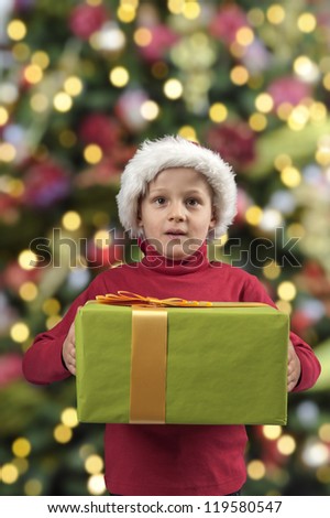 child with christmas present and hat, xmas tree background