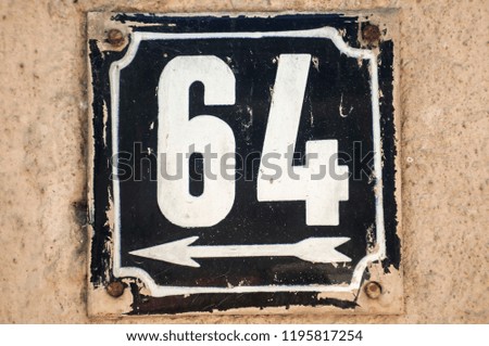 Weathered grunge square metal enameled plate of number of street address with number 64 closeup
