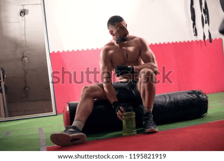 Boxer resting with water after training, sitting on the punching