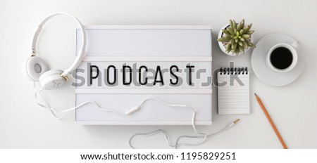 Podcast word on lightbox with headphones, notepad and coffee cup, podcast concept, flat lay
