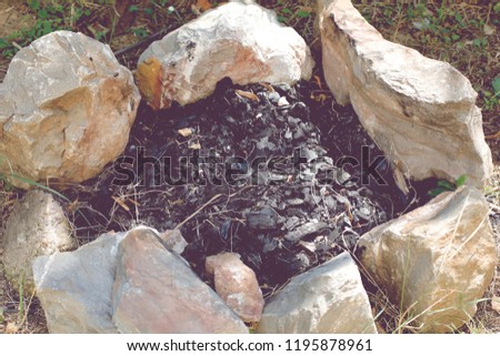 beautiful photo of old stone fire pit whit ashes in nature on sunny summer day