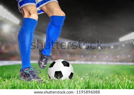 Soccer player in action with football in brightly lit outdoor stadium. Focus on foreground and soccer ball with shallow depth of field on background and copy space.