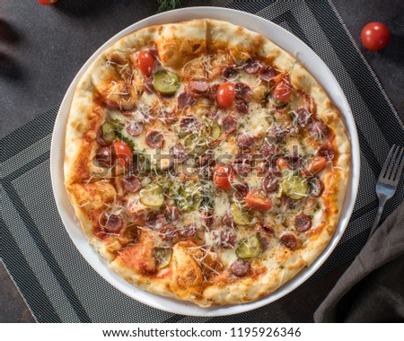 Appetizing pizza with salami, onions and gherkins and crunchy crust, top view with copy space. Italian food, restaurant menu concept