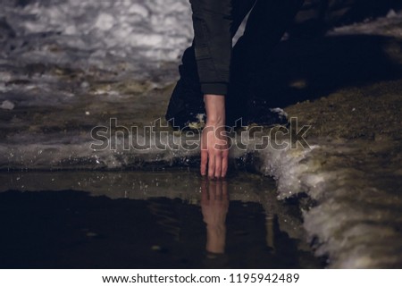 man tries hand cold water temperature in river, surface of reservoir forged ice during winter, hole with free surface of water for bathing Northern hardened man, swimming with frostbite, catch a cold