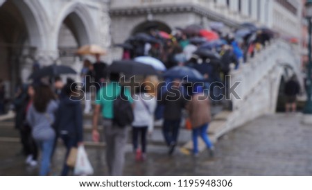 Tourists walking on arched bridge in Venice, Italy while holding umbrellas
