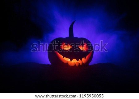 Halloween pumpkin smile and scrary eyes for party night. Close up view of scary Halloween pumpkin with eyes glowing inside at black background. Selective focus