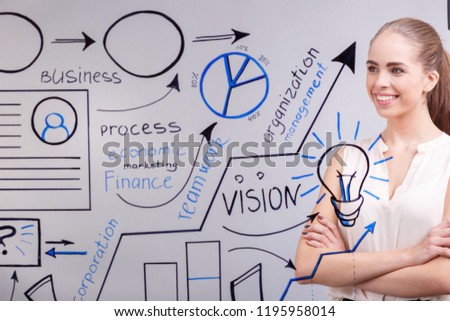 A young happy businesswoman writing on a transparent board in the office, close-up. Business presentations concept