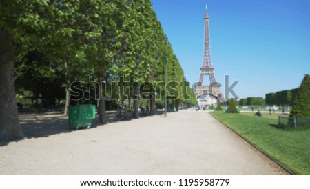 Blurred background plate of walkway at park by Eiffel Tower on sunny day
