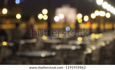 Out of focus background plate of outdoor cafe tables at night with bokeh lights