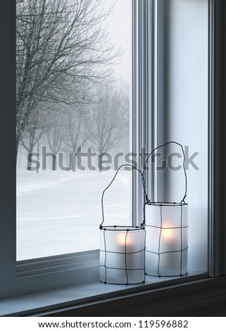 Cozy lanterns on a windowsill, with winter landscape seen through the window. Royalty-Free Stock Photo #119596882