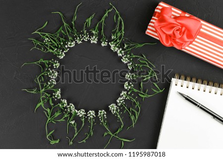 decorative background of flowers in a circle on a black background with gifts top view, flat lay, white flowers on a black table