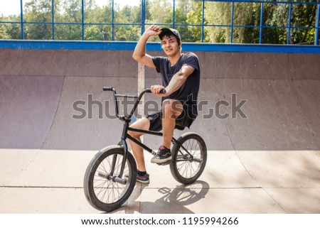 Rider resting on bmx, sitting on cycle in skate park