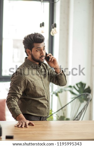 Indian businessman talking on phone in modern office