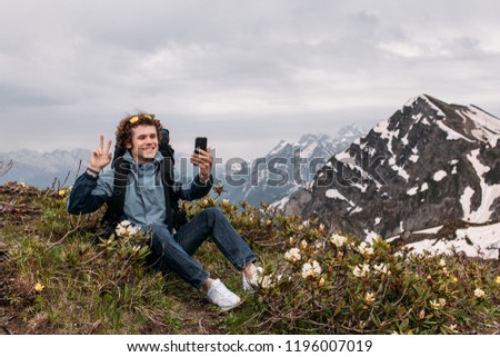 young positive hiker with victory gesture is taking a selfie. amazing breathtaking scinery on the background