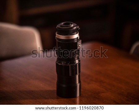 A vintage 35 mm telephoto lens on a table with the aperture, focus rings, and f-stop visible. 