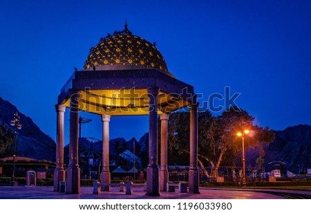 Gazebo dome bathed in yellow light. A romantic atmosphere during blue hour, from Muscat, Oman.