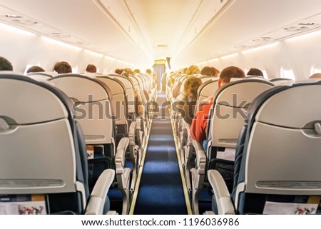 Commercial aircraft cabin with rows of seats down the aisle. morning light in the salon of the airliner. economy class Royalty-Free Stock Photo #1196036986