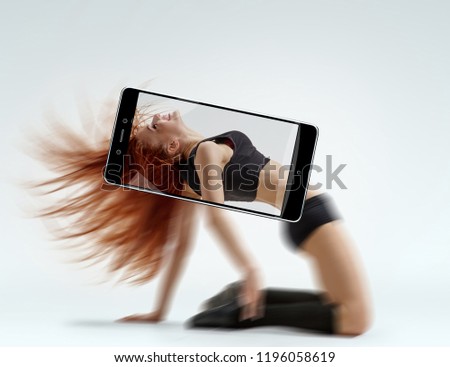 Young beautiful ballet dancer training on white background. conceptual image with a smartphone, demonstration of device capabilities