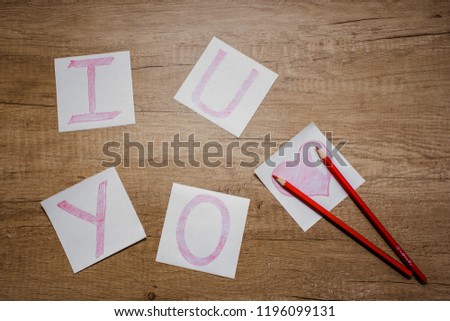 
Valentine's Day - the inscription "I Love you", drawn with pencils on white paper on a wooden background