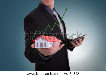 Businessman hand holding house representing home ownership and the Real Estate business with tablet. Mortgage concept