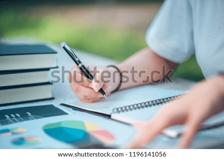 Woman sitting at desk and working at hand of book and financial documents close up