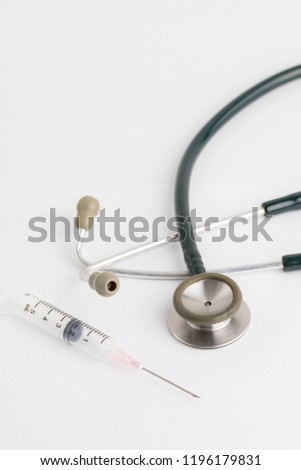 Stethoscope and injection needle on white background.