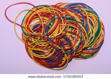 A pile of multi-colored rubber bands stationery, ready to use, is disordered mass on a white plane, close-up, instagram.