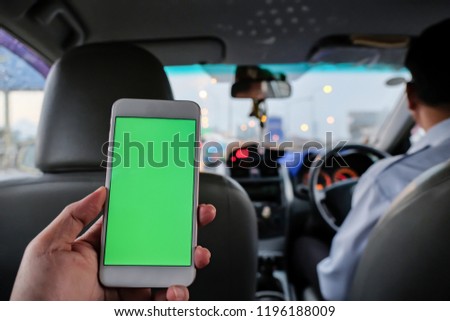 Passenger in back seat of Taxi with smartphone in hand for use mobile application.