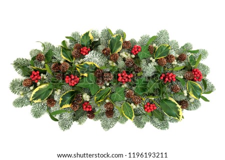 Christmas and winter natural table decoration with holly berries, snow covered spruce pine, ivy, pine cones and mistletoe isolated on white background.